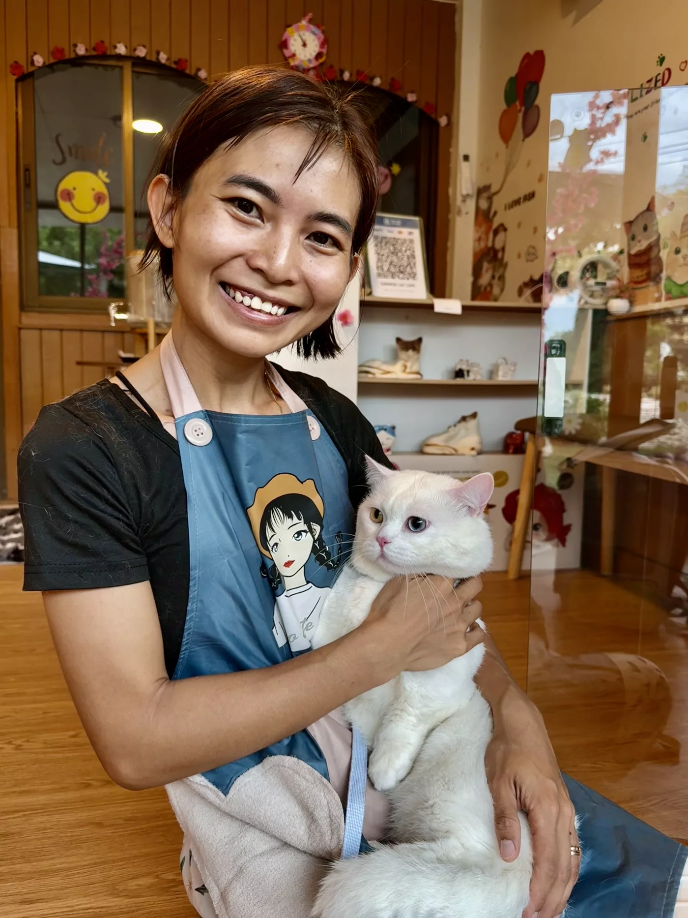 Сотрудница Siamese Cat Café держит белую кошку